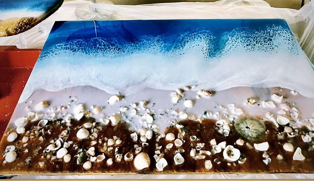 Ocean resin wall art with a foam line breaking against a sand-toned shore